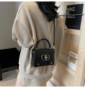 Detailed view of black leather crossbody bag with embossed patterns and gold ring buckle