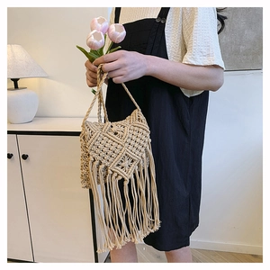 Close-up of handmade bohemian woven cotton rope bag featuring long tassel decorations