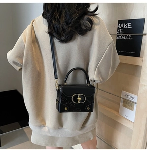 Close-up of black leather crossbody bag featuring embossed bear patterns and gold clasp