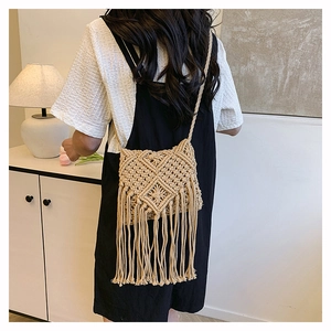 Detailed shot of beige woven crossbody bag with long tassels and diamond knit pattern