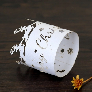 Detail of white laser-cut reindeer and snowflake paper napkin rings for Christmas table
