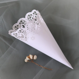 Close-up of laser-cut white wedding confetti cones with heart lace hollow pattern
