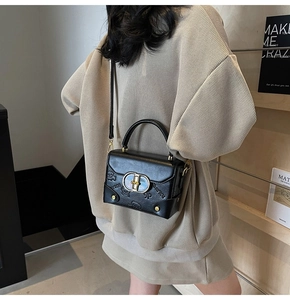 Detail of black leather handbag with unique cartoon embossed pattern and gold buckle