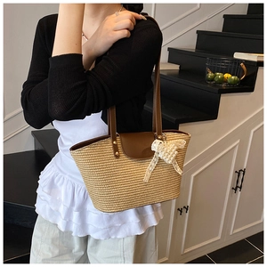 Detail of handwoven straw bag with brown leather flap and a white lace bow accent