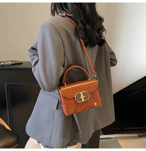 Detail of a brown crossbody bag with bear embossing and a gold metal twist lock closure