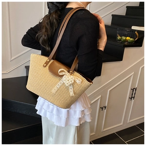 Detailed shoulder view of handmade woven beach bag with lace bow and pearl charms