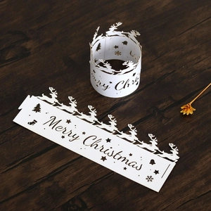 Close-up of laser-cut white paper Christmas cake wrap with reindeer and snowflake patterns