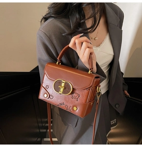 Close-up of brown textured leather bag with metallic twist lock and embossed teddy bear detail