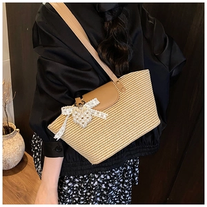 Detailed close-up of woven straw bag with lace bow and pearl heart pendant charm
