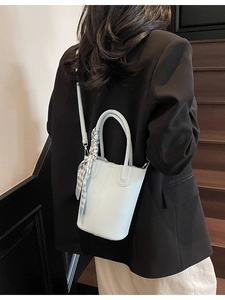 Light blue bucket bag with pebble leather and plaid scarf shown on a model
