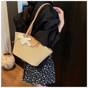 Close-up of straw tote bag with lace pearl bow and premium brown leather straps