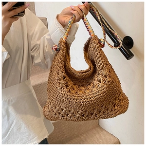 Gros plan du sac hobo bohème tissé avec poignée colorée et pompons décoratifs