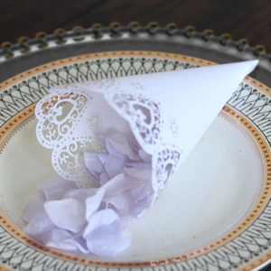 Detail of laser cut lace paper cone with silk lavender petals for wedding decor