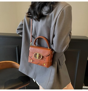 Detail of vintage brown leather handbag with cartoon embossing and gold metal clasp