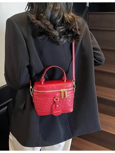 Red woven leather bucket bag with gold zippers shown on a model on wooden stairs