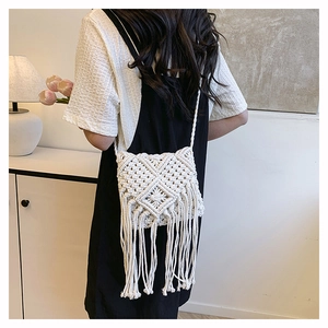 Detailed close-up of a white hand-woven crossbody bag with long tassels and geometric texture