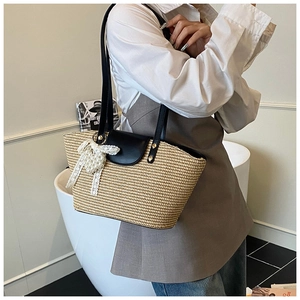Detail of hand-woven straw tote with black leather flap and lace bow charm