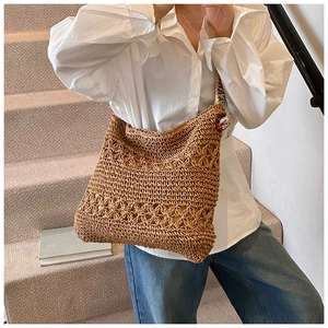 Détail d'un sac cabas tissé marron avec motif floral ajouré et pompon arc-en-ciel