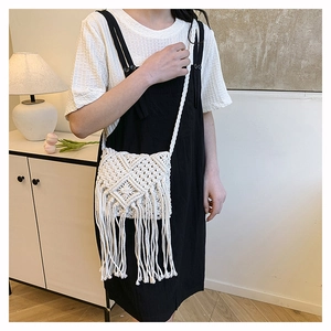 Detail of handmade cream cotton crochet crossbody bag with bohemian tassel and woven strap