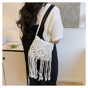 Detail of handmade cream woven crossbody bag with bohemian cotton tassels and knit patterns