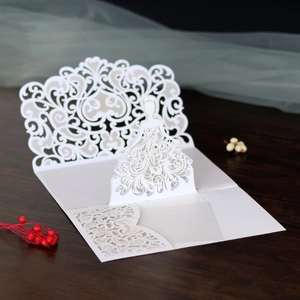 Macro shot of 3D laser-cut lace bridal invitation card with intricate vine patterns