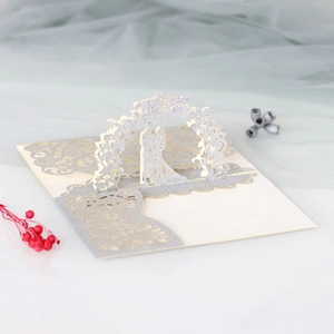 Detail of 3D laser cut wedding invitation showing glittery silver arch and couple silhouette