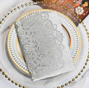 Detail of silver glitter laser-cut floral invitation on marble background with pearls