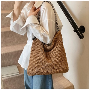 Détail d'un grand sac cabas en paille tressée avec bandoulière à motifs géométriques