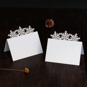 Laser-cut white snowflake place card made of pearlescent paper on a rustic wooden table
