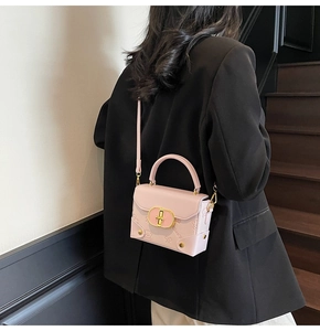Detail of light pink mini satchel with teddy bear embossing and gold buckle on a model