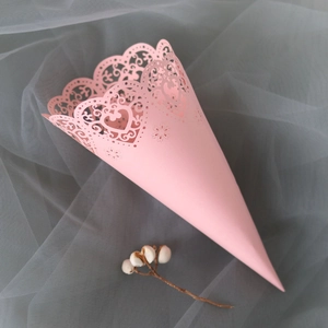 Close-up of pink laser-cut paper cone with heart pattern for wedding confetti