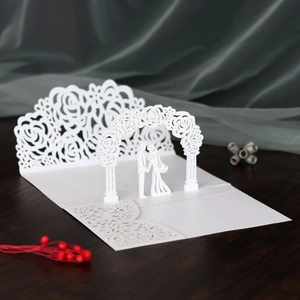 Detailed laser-cut 3D pop-up wedding invitation featuring white lace flowers and couple