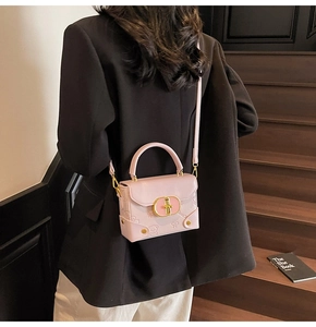 Detailed back view of pink leather crossbody bag with embossed patterns and metal handle