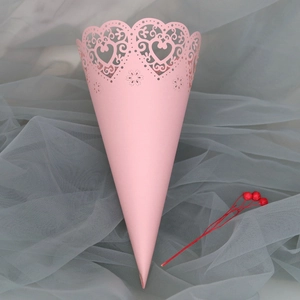 Close-up of pink laser-cut paper cone with heart lace patterns on mesh background