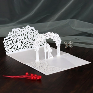 Macro detail of laser-cut 3D wedding invitation with couple under rose arch
