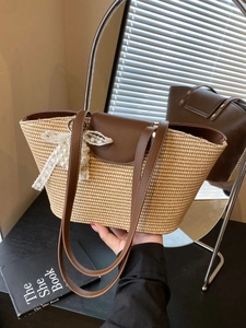 Handwoven straw tote bag with brown leather straps and elegant pearl lace pendant