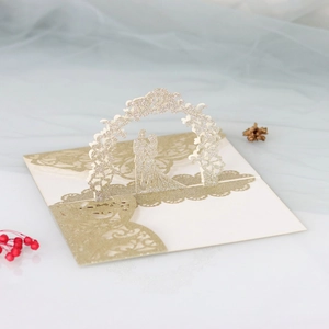 Intricate laser cut 3D wedding card with gold glitter couple under a floral arch