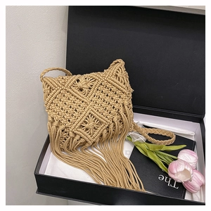 Detail of khaki macrame crossbody bag with woven texture and tassels in a gift box