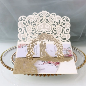 Detail of laser-cut wedding invitation with gold glitter finish and floral inner card