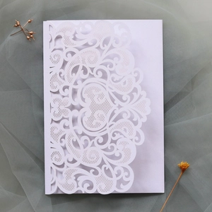 Detailed view of white laser-cut wedding invitation featuring elegant floral patterns