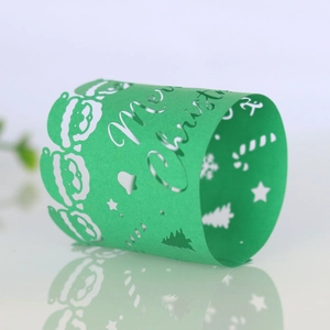 Detail of green laser-cut Christmas napkin ring featuring Santa and festive tree patterns