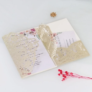 Macro detail of laser-cut glitter gold wedding invitation with floral printed insert card