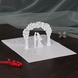 Macro view of white laser-cut wedding invitation featuring a 3D bridal couple silhouette