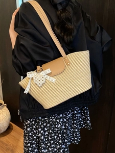 Handwoven summer straw tote bag with brown leather straps and pearl bow charm detail