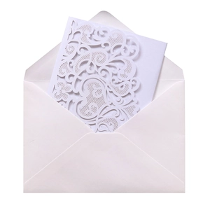 Macro shot of laser-cut lace invitation set with elegant scrolls and white envelope
