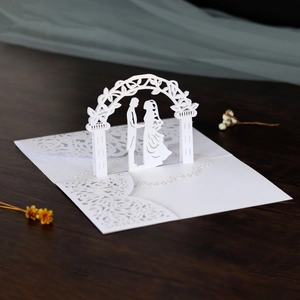 Dettaglio dell'invito di nozze 3D tagliato al laser con sposi sotto un arco floreale