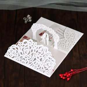Detailed macro view of laser-cut white 3D pop-up wedding invitation with floral arch