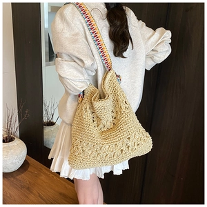 Détail du sac cabas en paille tissé avec bandoulière bohème colorée sur un modèle