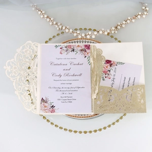 Detail of laser-cut wedding invitation with glitter finish and floral inner card