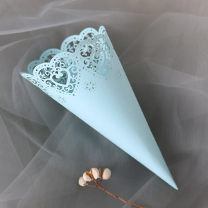Detailed laser-cut heart pattern on a light blue wedding confetti cone of kraft paper
